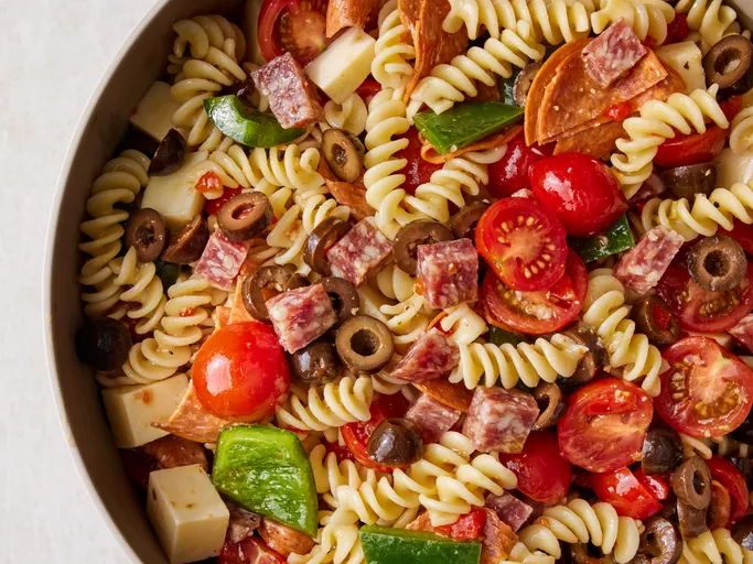 a bowl of pasta salad with tomatos and salami